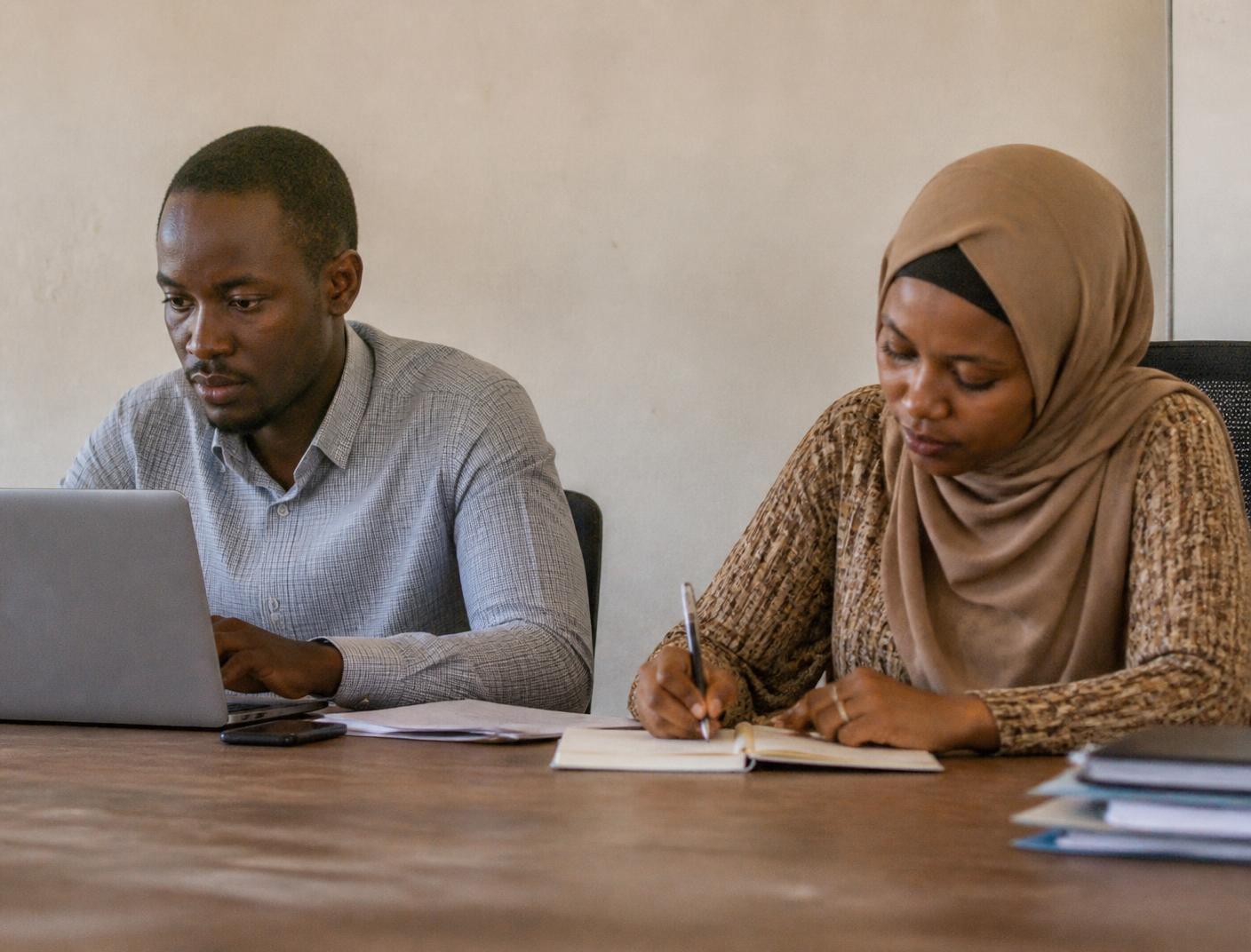 Two Pristine Consultancy consultants working at a table in their Dar es Salaam office